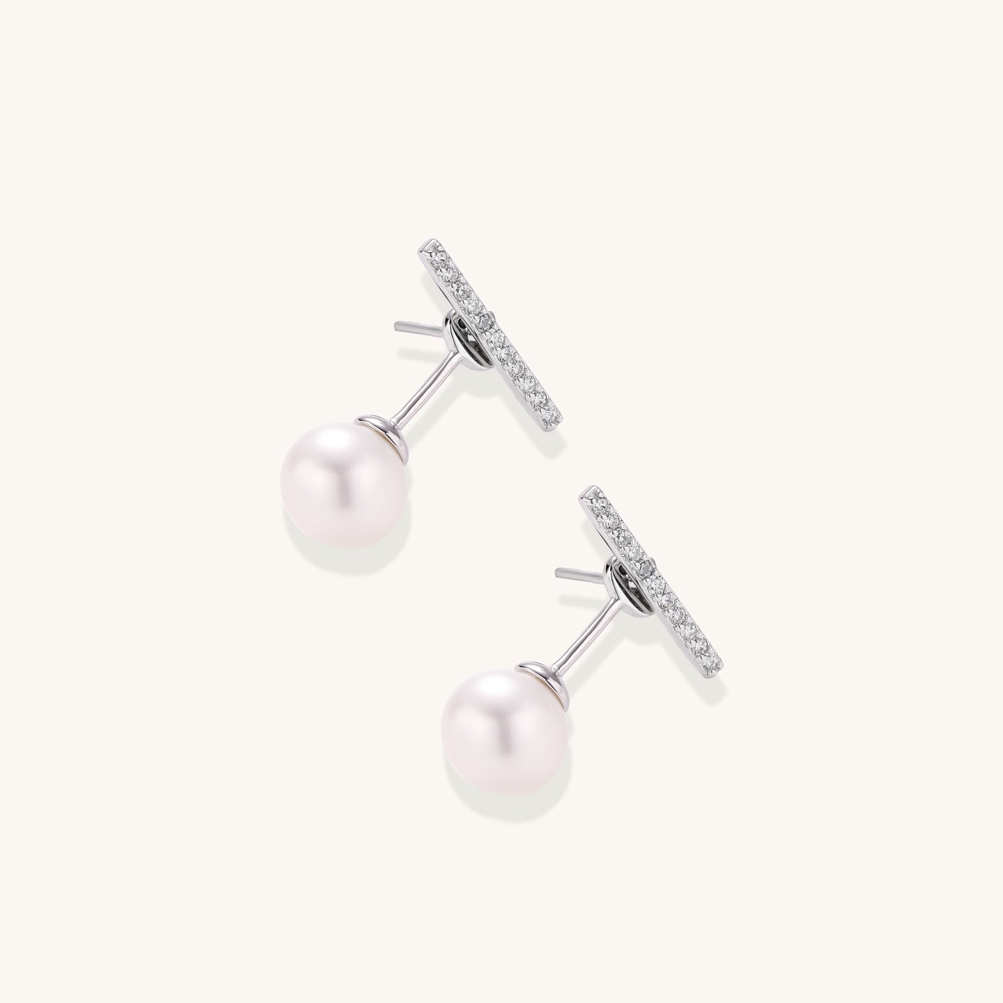 Sterling silver bar stud earrings with freshwater pearl drops on white background, minimalist jewelry design