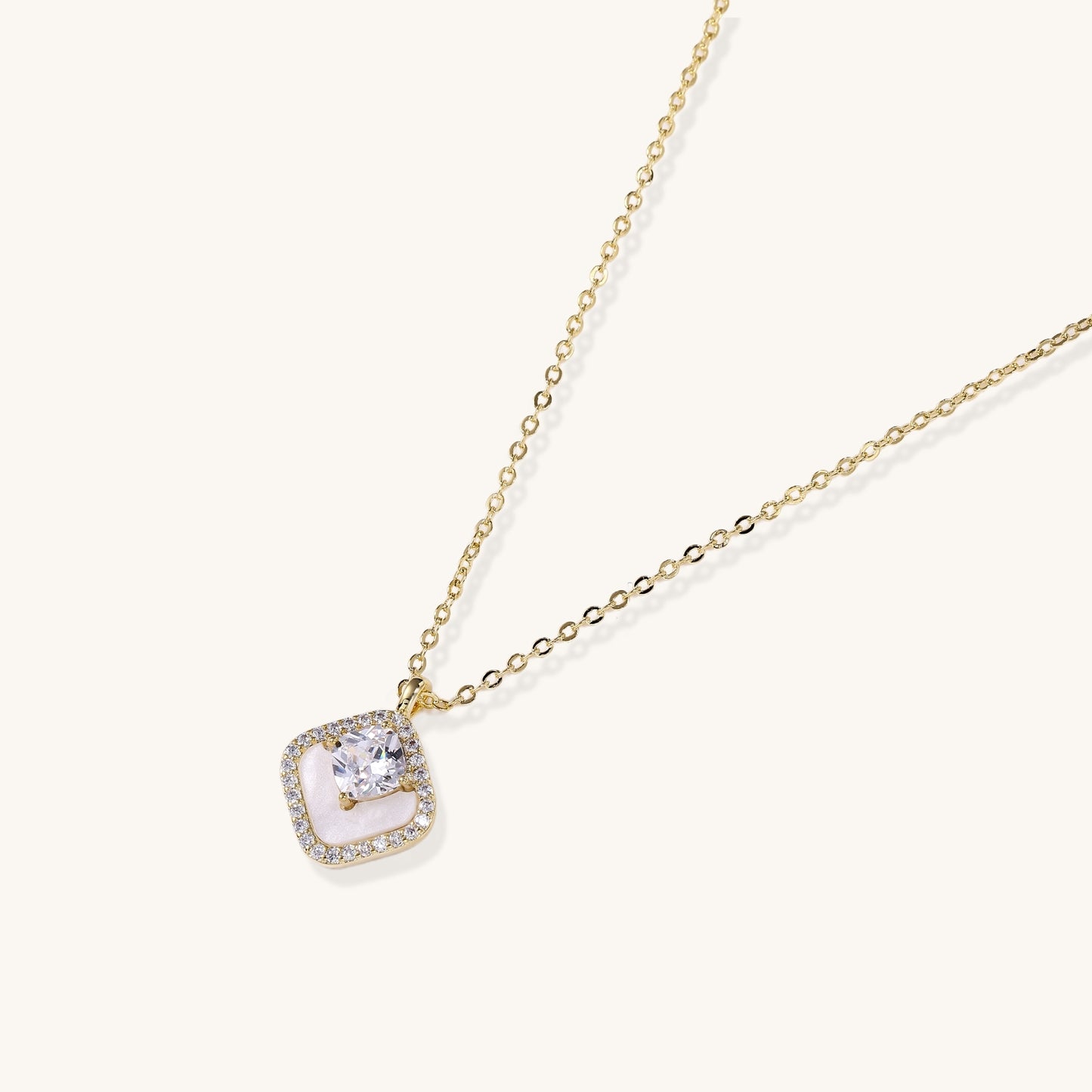 Gold-plated necklace with cushion-shaped pendant featuring a freshwater pearl surrounded by crystal halo on white background.