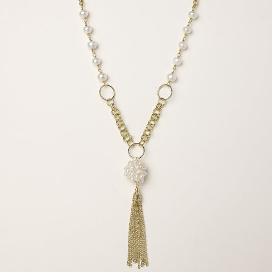 Layered gold-plated necklace with freshwater pearls, central pearl cluster, and chain tassel on cream background.