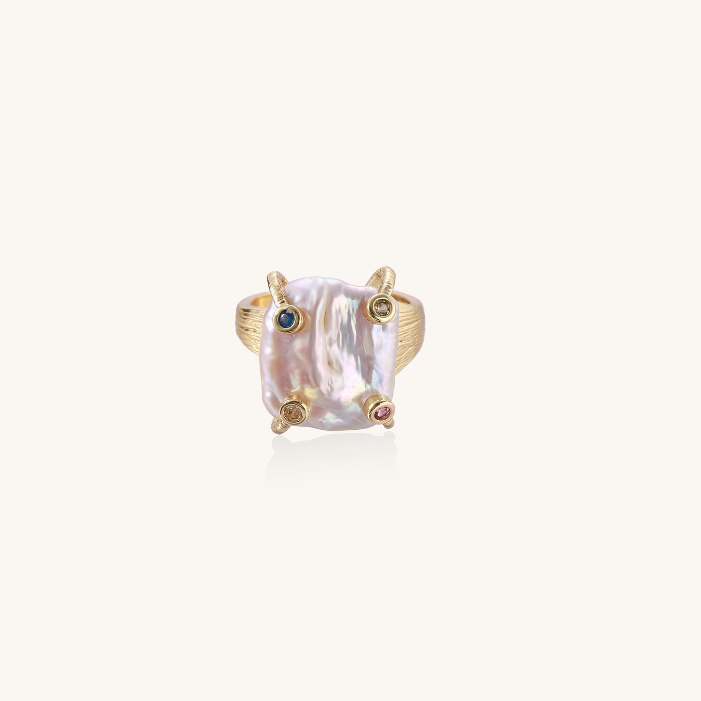 Gold-plated ring featuring large baroque freshwater pearl with small colorful gemstone accents on textured band