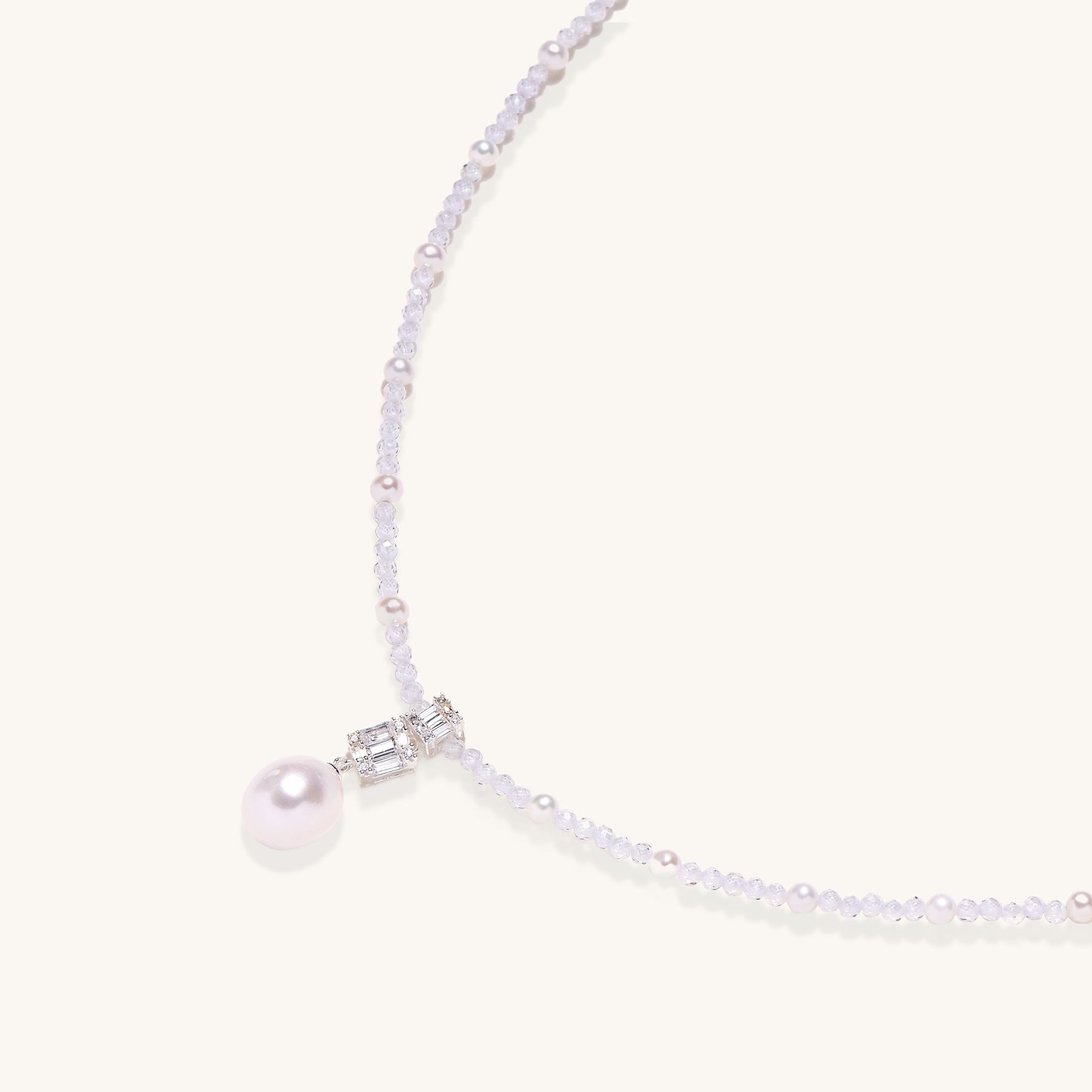 Delicate beaded necklace with lavender crystals, white pearls, and crystal pendant with pearl drop on white background.