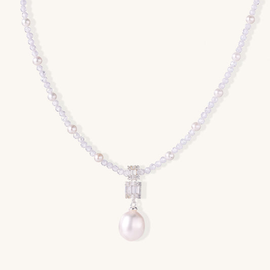 Delicate beaded necklace with lavender crystals, white pearls, and crystal pendant with pearl drop on white background.