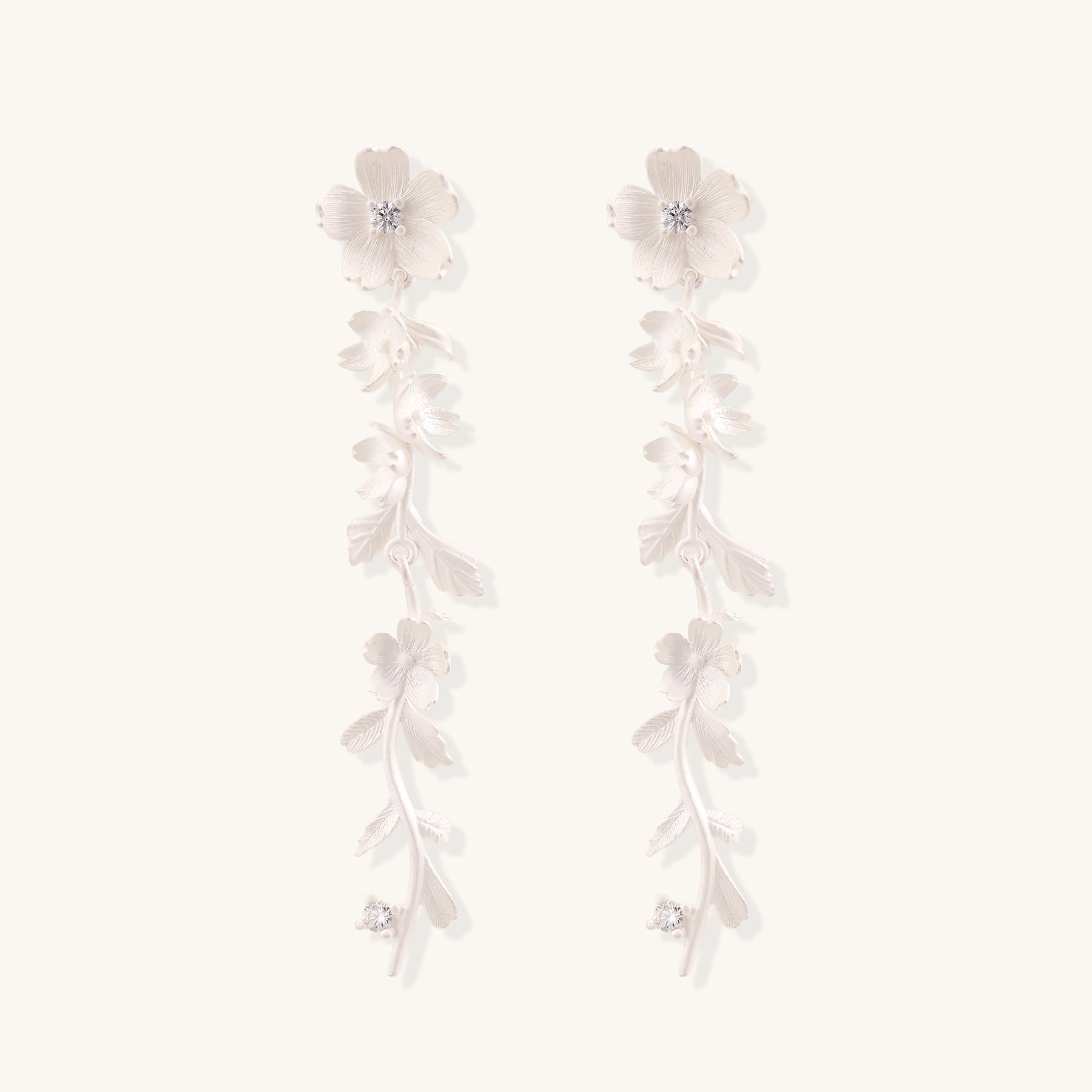 Pair of sterling silver dangle earrings with intricate leaf vine patterns and crystal accents on white background.