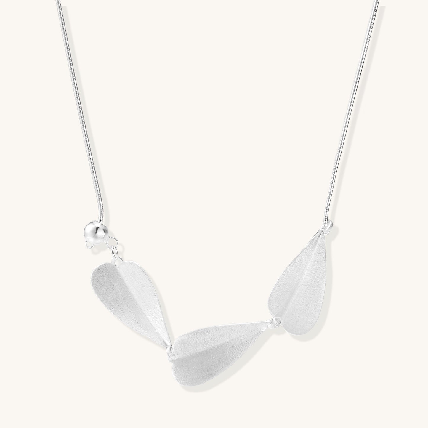 Delicate sterling silver necklace with brushed leaf pendants distributed along a fine chain on white background.