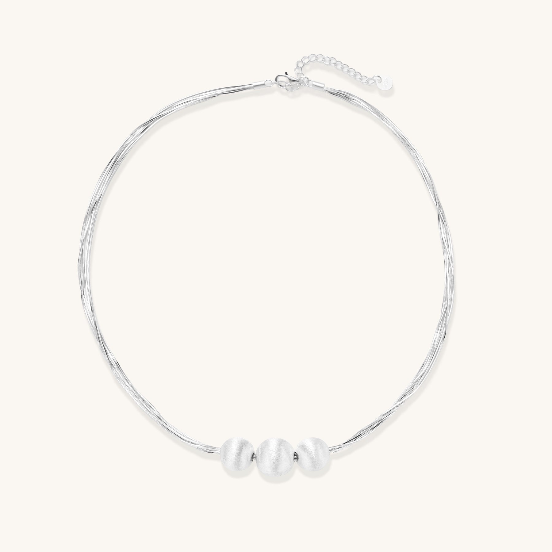 Multi-strand sterling silver necklace with three polished round beads clustered at center on white background.