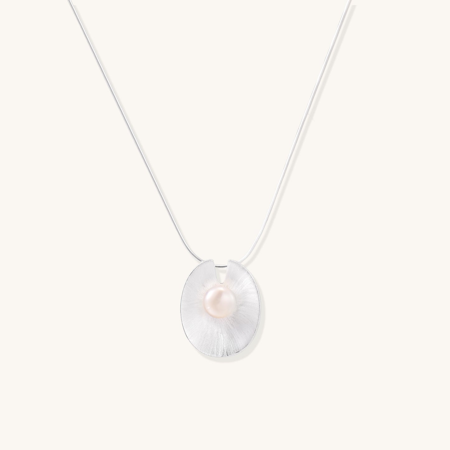 Delicate sterling silver necklace with oval iridescent pendant and central freshwater pearl on white background