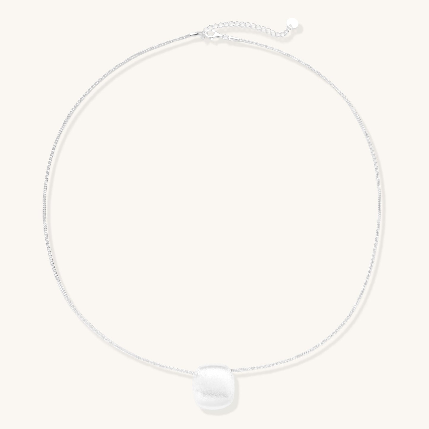 Minimalist sterling silver necklace with brushed square pendant on adjustable chain against white background.