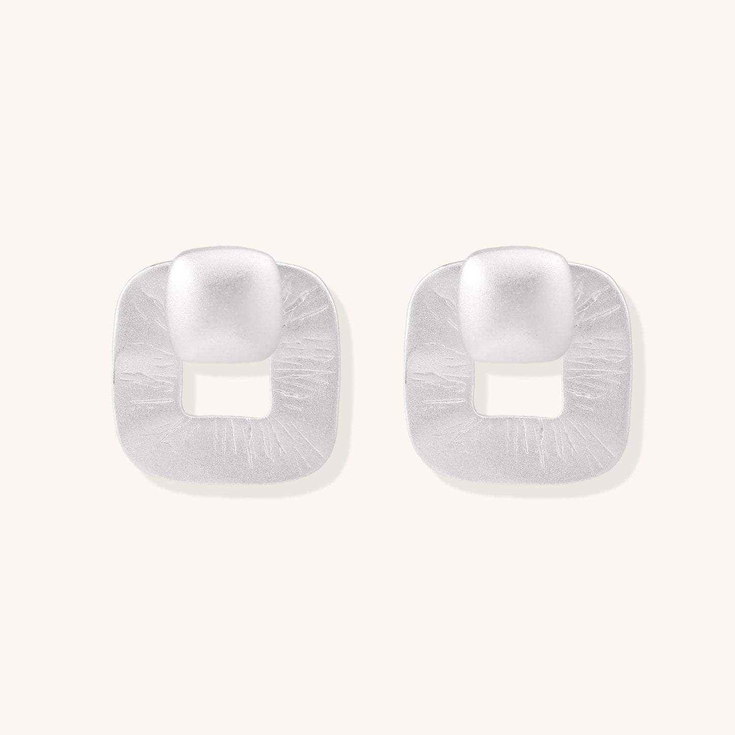 Geometric sterling silver square stud earrings with brushed texture and central square cutouts on white background.