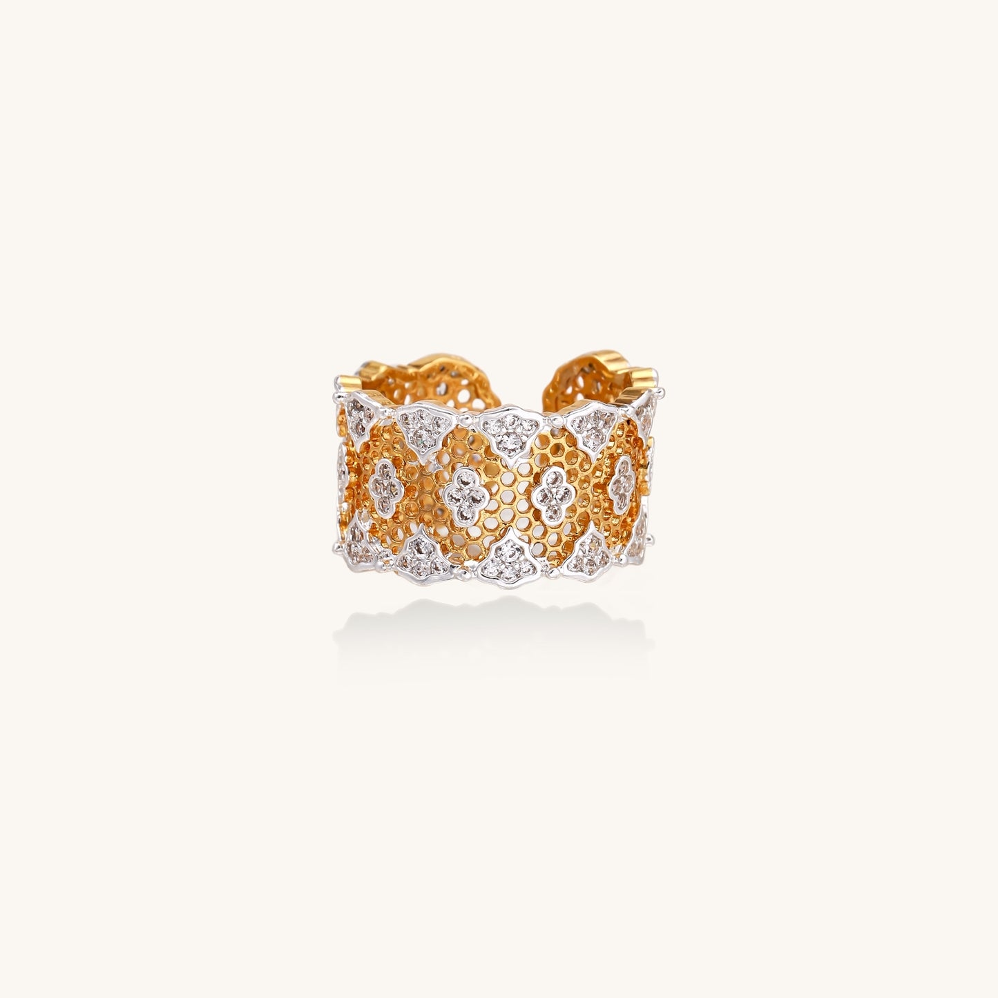 Wide gold-plated ring featuring intricate honeycomb mesh pattern with scattered zirconia stones on cream background