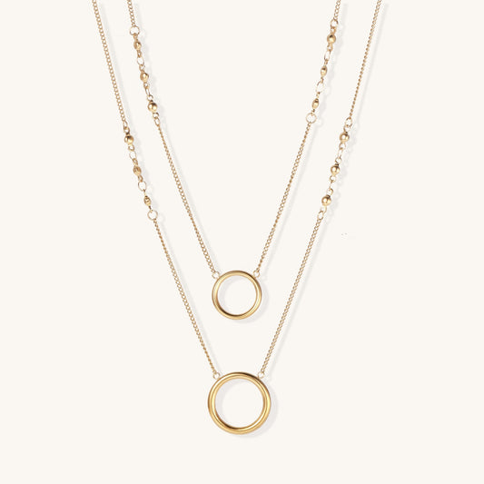 Gold-plated layered necklace set with two circular pendants featuring white centers on delicate chains.