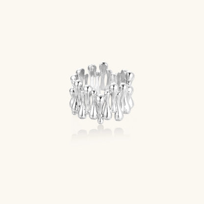 Wide band ring with sculptural wave ripples in polished white gold plated eco-brass on cream background